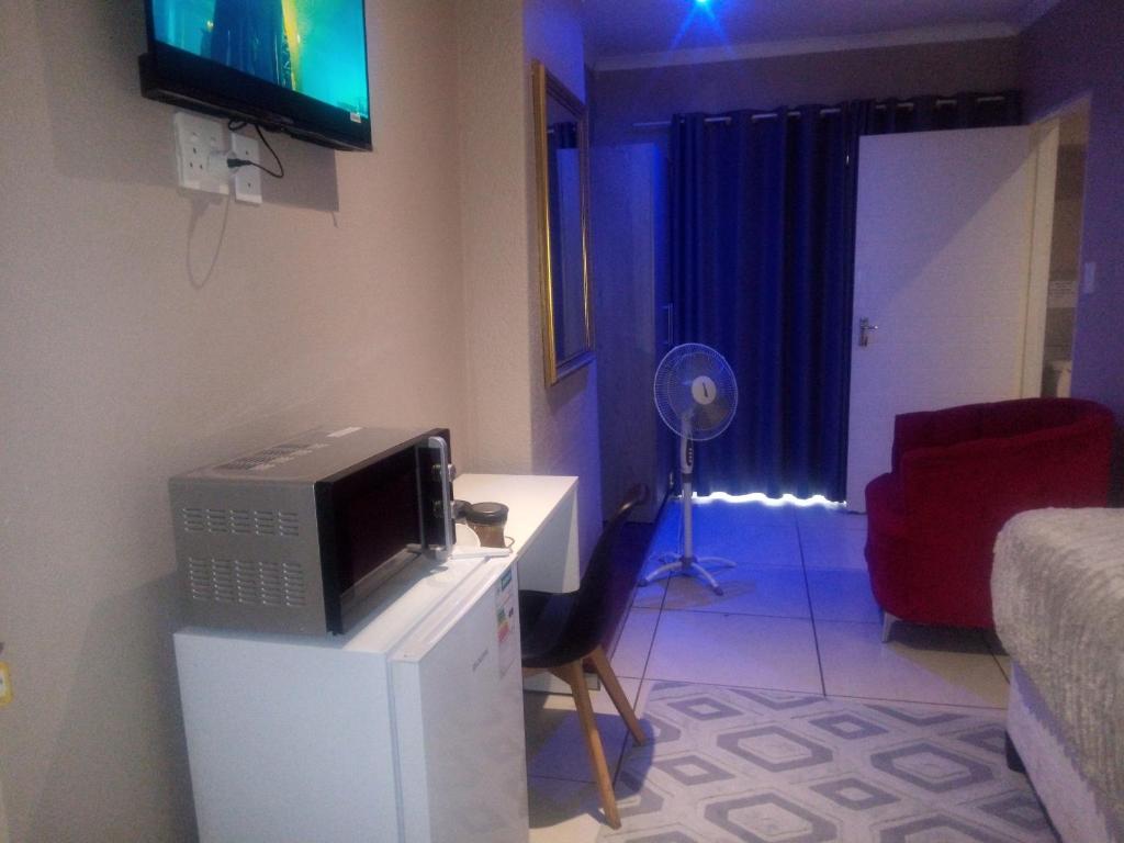 a living room with a tv on top of a refrigerator at B&P Guesthouse in Boksburg
