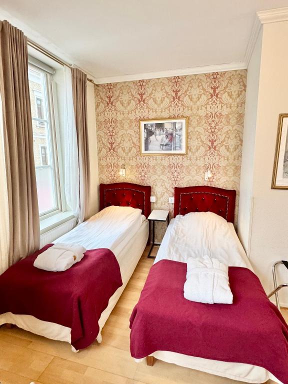 Dwie pojedyncze łóżka z czerwonymi zagłówkami i bordowymi narzutami w eleganckim pokoju