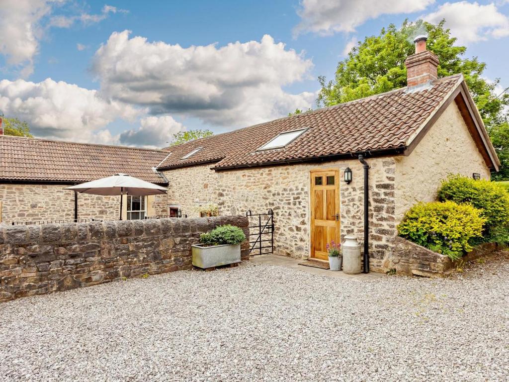 a stone cottage with a stone wall and a wooden door at 4 Bed in Frome oc-27808 in Holwell