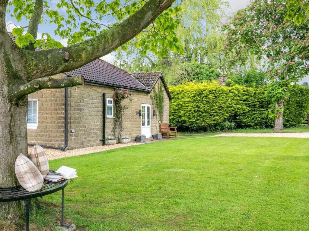 a book on a bench under a tree in a yard at 2 Bed in York oc-84000 in Crayke