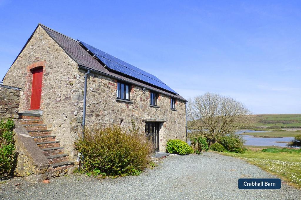 an old stone building with a red window and stairs at Crabhall Barn in Haverfordwest