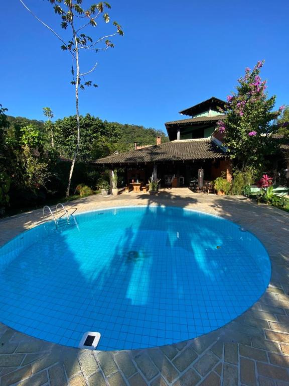 a large blue swimming pool in front of a house at Casa Jataí Guest House in Barra do Sahy