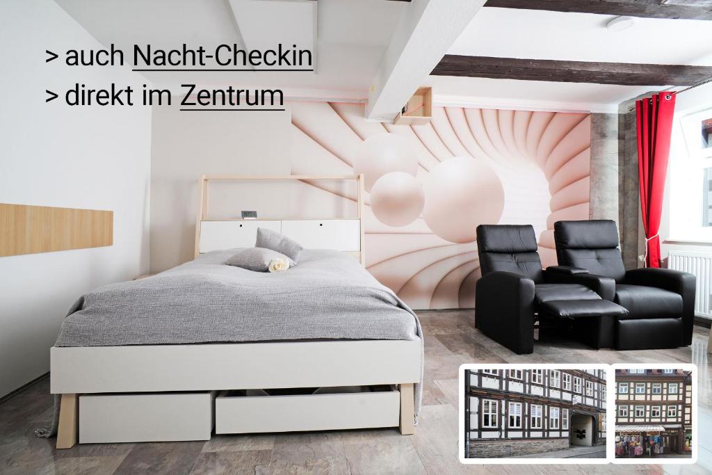 a bedroom with a bed and two chairs at Design-Ferienwohnungen Stadtidyll in Wernigerode