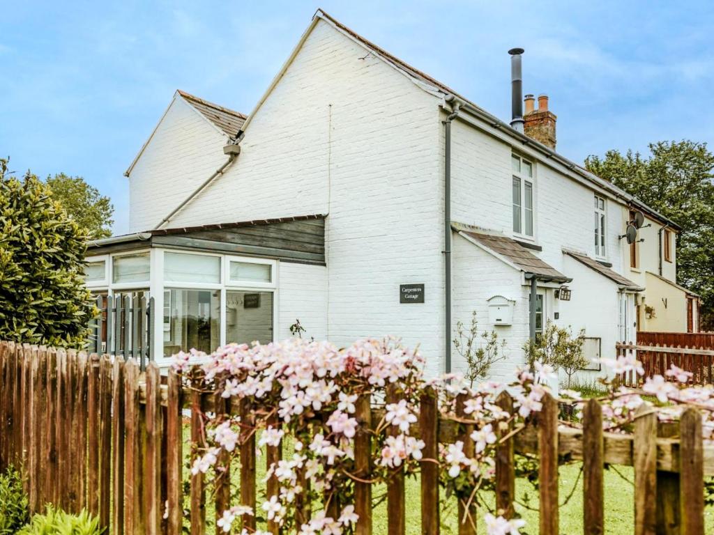 a white house behind a fence with pink flowers at 2 Bed in St Helens oc-76608 in Brading
