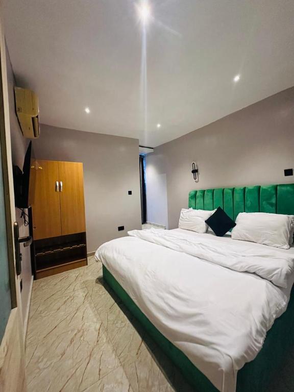 a bedroom with a large bed with a green headboard at FortExcel Hotels & Suites in Odogun