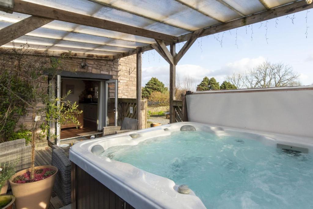 a jacuzzi tub in a backyard with a pergola at Ffynnonlwyd Cottage - rural holiday cottage with hot tub in Llangynin