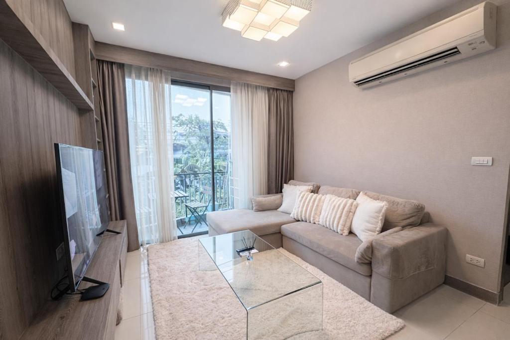 a living room with a couch and a glass table at Spacious 2BR Condo with 2 Balconies in Sukhumvit16 in Bangkok