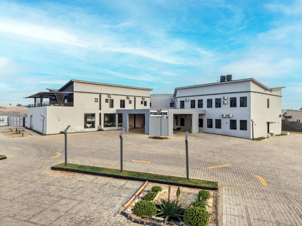 a large white building with a parking lot at Peregrine Hotel Jos in Jos