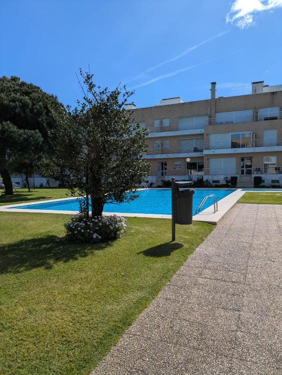 a tree in the grass next to a building at Descanso, Mar & Conforto in Esposende