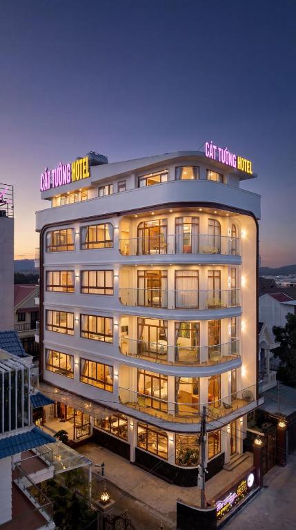 a tall white building with a sign on it at Cát Tường Hotel in Da Lat