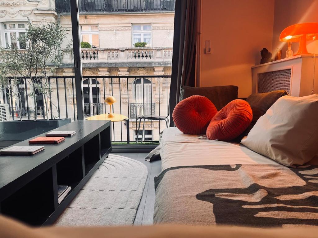a room with a couch with red pillows and a window at Stylish studio 3-4p with AC and balcony near Champs-Élysées in Paris