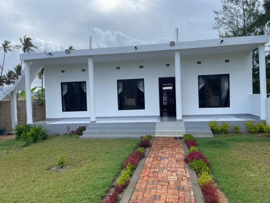 a white house with a brick pathway in front of it at Carinho da Paz in Inhambane