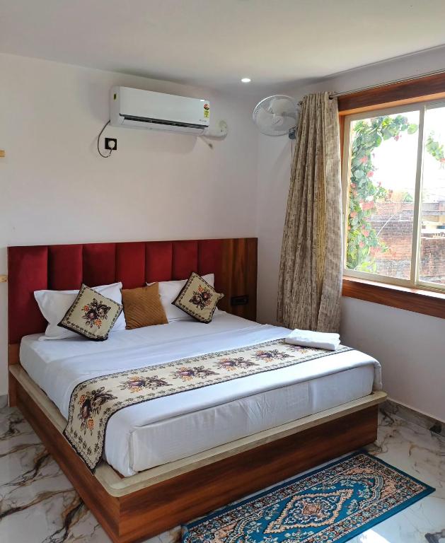 a bedroom with a bed with a red headboard and a window at Orchha Best Homestay in Orchha