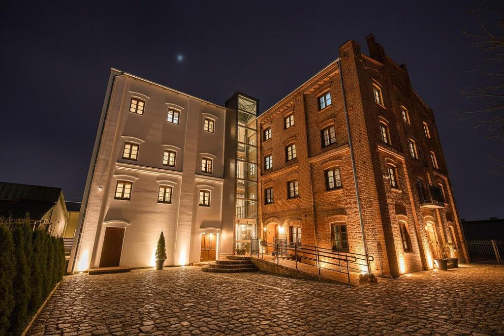 a large brick building next to a tall building at Młyn Melzak in Pieniężno