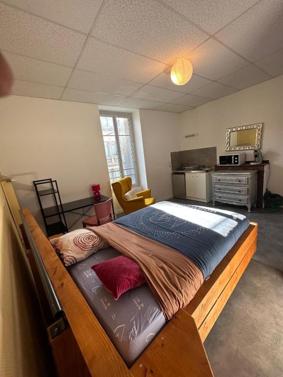 a large bed in a room with a kitchen at Hôtel de la gare - Petit Studio in Tarbes