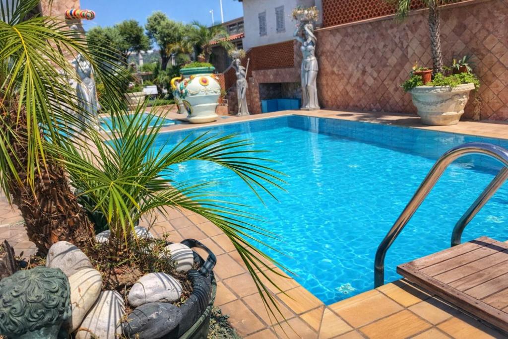 a large swimming pool with a palm tree next to it at Hotiday Villa Neptunus in Forio d'Ischia