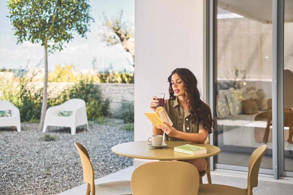 a woman sitting at a table reading a book at Wanderlust Experience Costa Sud in Bari