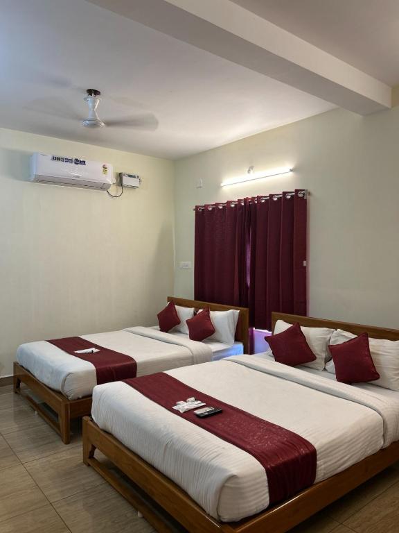 two beds in a hotel room with red curtains at Villa The De Grise in Pondicherry