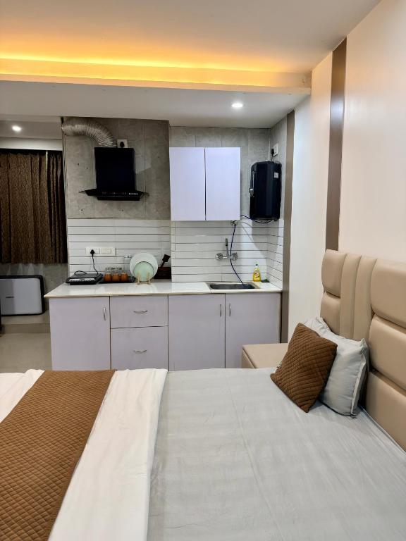 a bedroom with a large white bed and a kitchen at Halo Haven in Dehradun