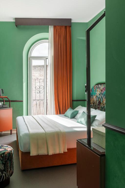 a bedroom with a bed with an orange curtain and a window at Barberini Retreat Boutique Hotel in Rome