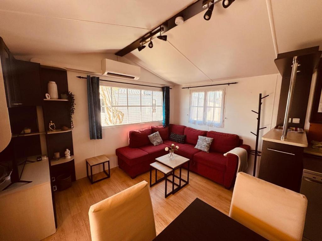 a living room with a red couch and a table at MH Camping la plage - MarieVa in Mimizan-Plage
