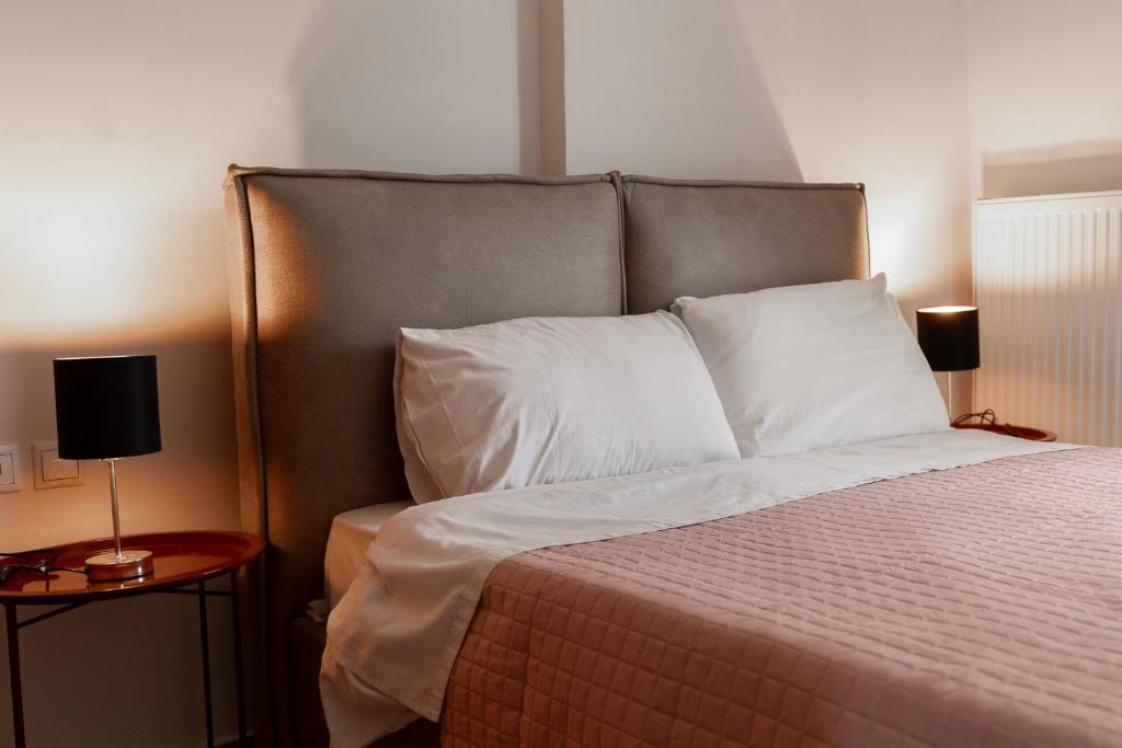 a bedroom with a bed with white pillows and two tables at Pineios View New Apartment in Larisa