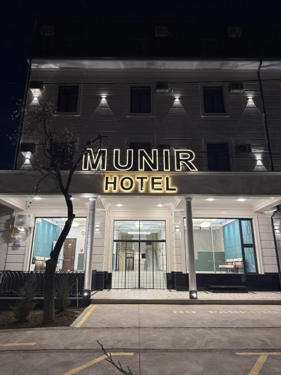 a hotel with a lit up sign on a building at Munir Hotel in Chilanzar