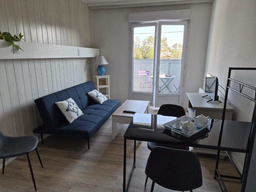 a living room with a blue couch and a table at le coulinet in Andernos-les-Bains