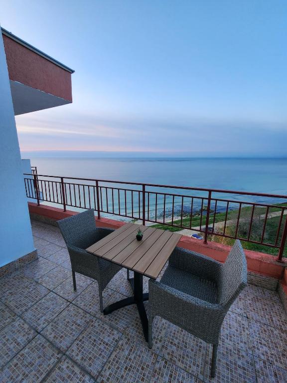a wooden table and chairs on a balcony overlooking the ocean at Stunning Beach View Apartment in Ravda