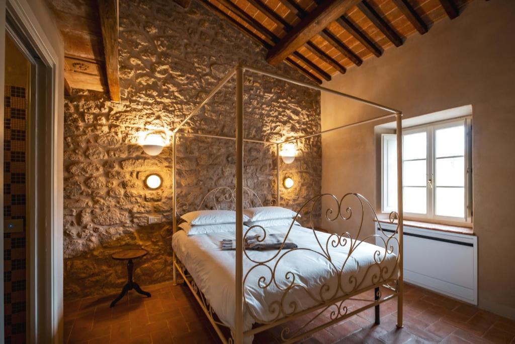 a bedroom with a metal bed in a stone wall at Casa in Campagna Casagori in Pienza
