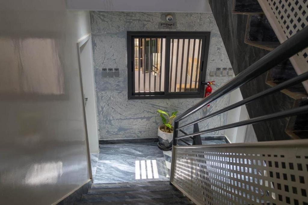 a hallway with a staircase with a window and a plant at Résidence Madior C2 in Dakar