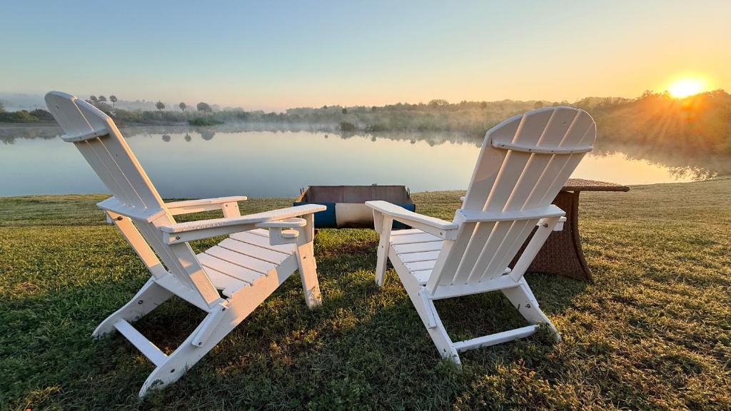two chairs sitting next to a table in front of a lake at The little Manatee Retreat in Orlando