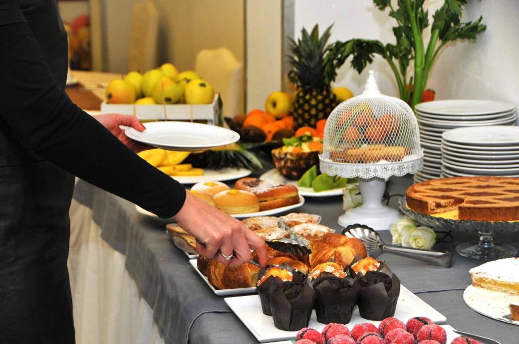 a person reaching for a tray of pastries on a table at Hotel Venezia in Caorle