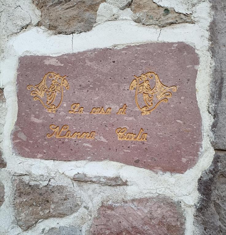a sign on a stone wall with two horses on it at La casa di Nonna Carta in Fordongianus