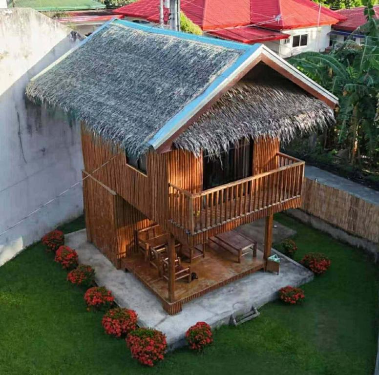 a small hut with a grass roof and some flowers at Brigitte´s Rental House in Dauin