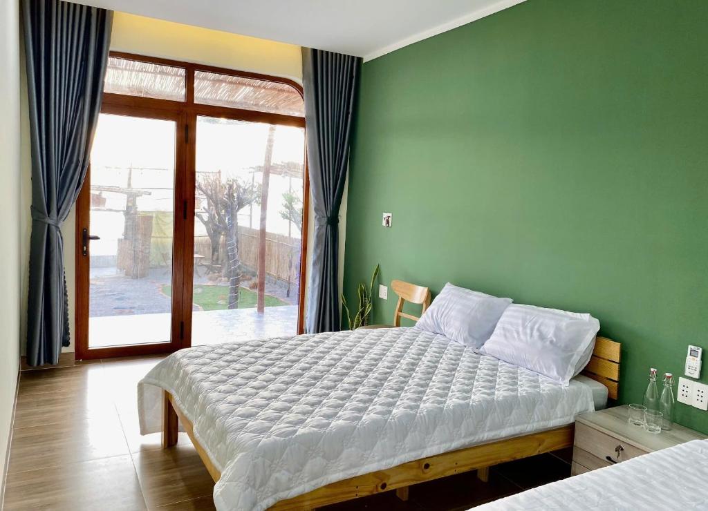a bedroom with a large bed and a green wall at Xóm Chài Homestay in Thôn Sơn Hải