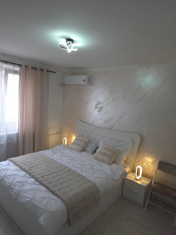 a bedroom with a large white bed with two lamps at Apartament Severin Caple in Drobeta-Turnu Severin