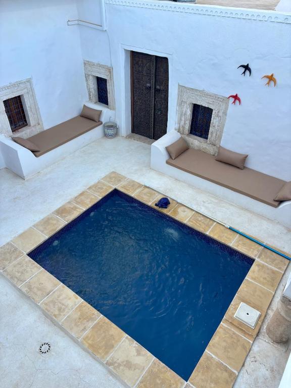 a swimming pool in a living room with two couches at Hoûch Les Anartistes in Erriadh
