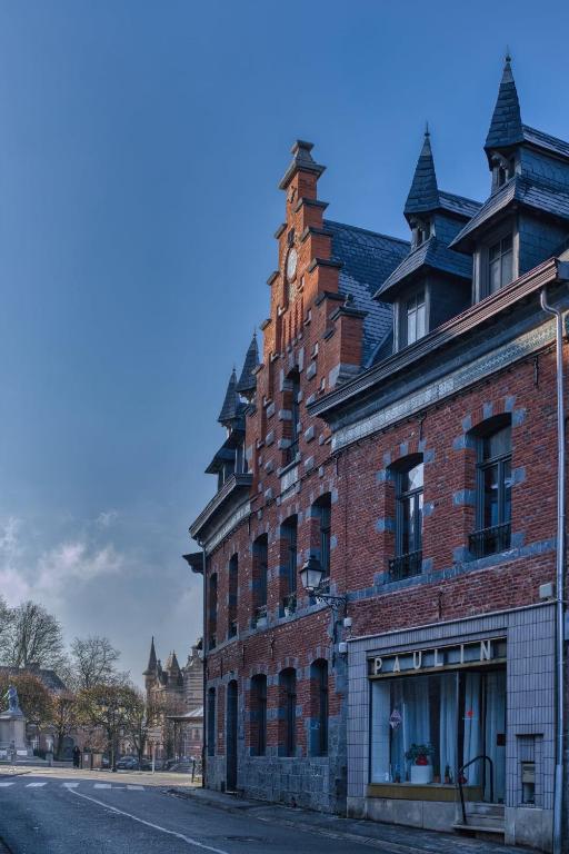 a red brick building with a clock tower on a street at Maison LE 2 in Solre-le-Château