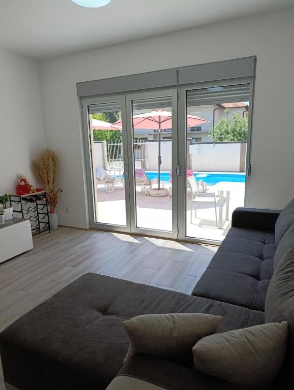 a living room with a couch and a view of a pool at Vila Komfor in Jajinci