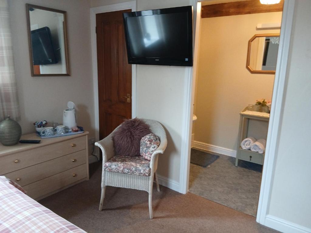 a bedroom with a chair and a television on a wall at Heskin Farm in Burscough