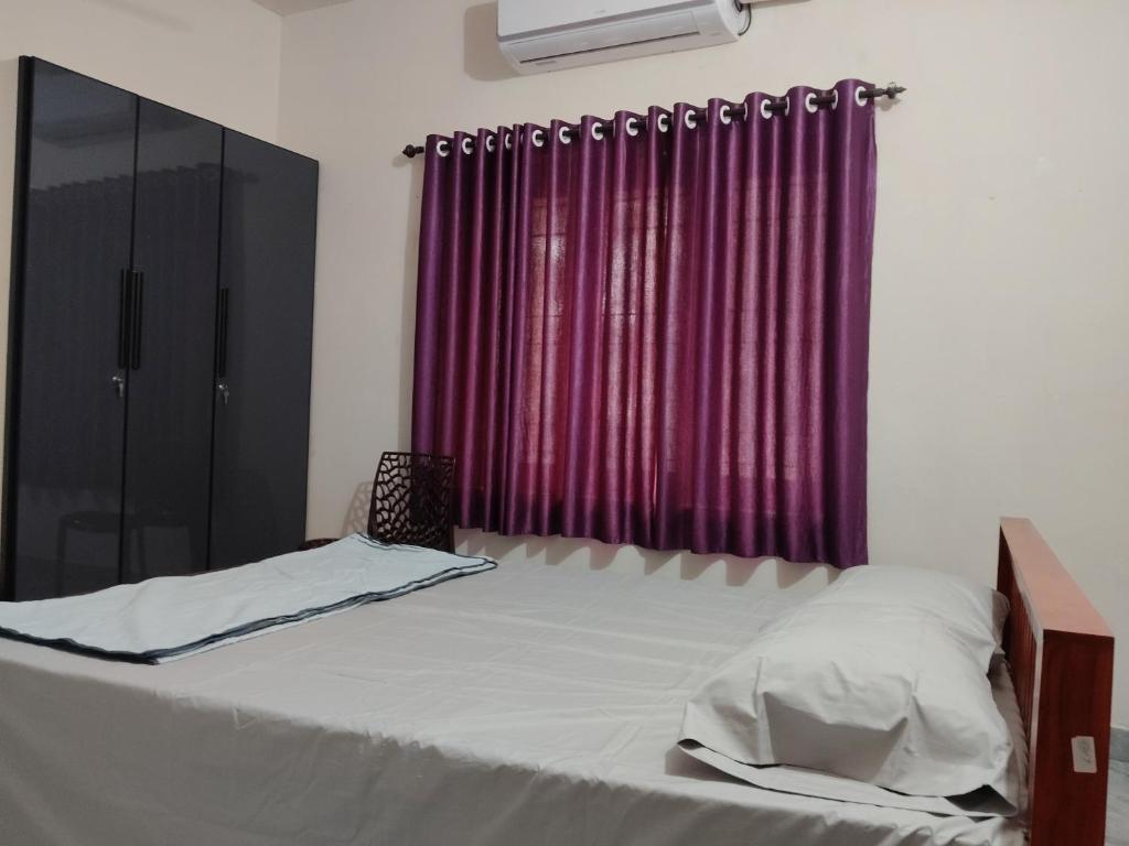 a bed in a room with a red curtain at Little Eden in Cochin
