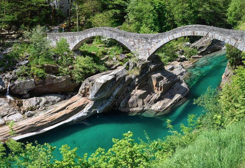 an old stone bridge over a river with blue water at Casa Hella by fewotessin in Lavertezzo