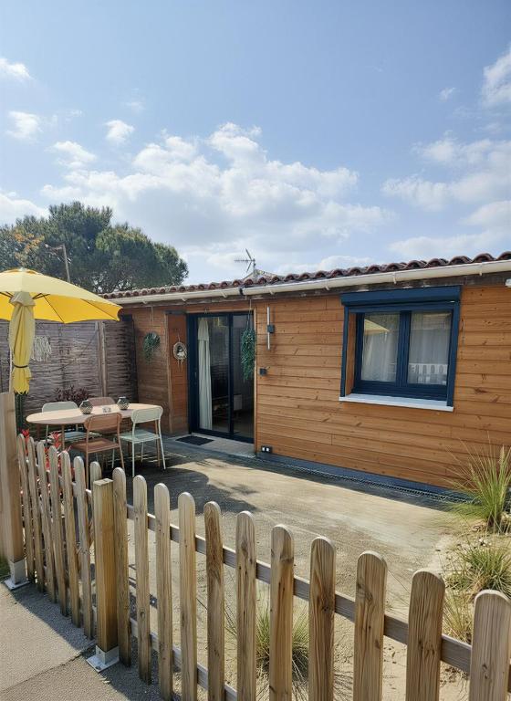 a house with a fence and a table and an umbrella at L'instant voyageur in Virsac