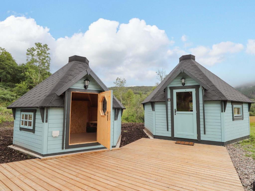 a shed with a thatched roof and a wooden deck at Little Luxe Lodges 2 in Balmacara