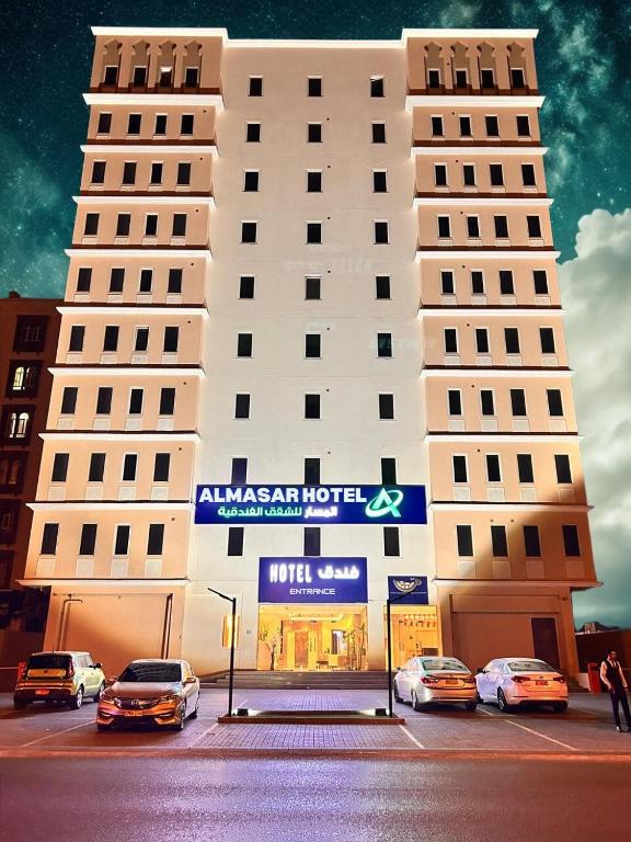 a large white building with cars parked in front of it at Almasar Hotel in Maţār as Sīb ad Duwalī