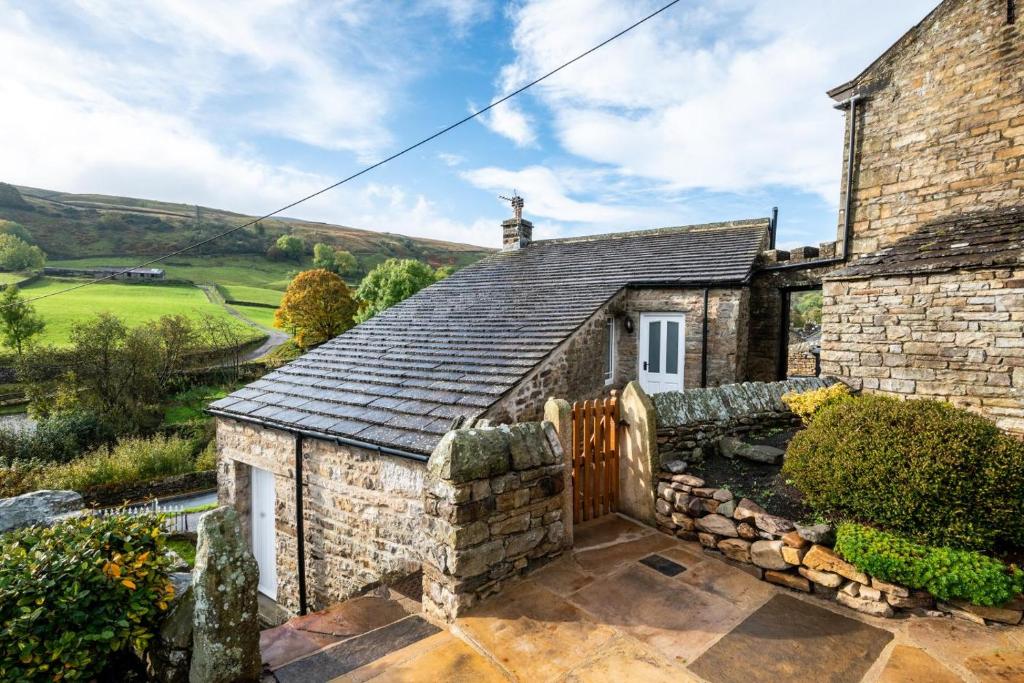 an old stone house with a gate and a fence at 5 Bed in Muker oc-ds1056 in Muker