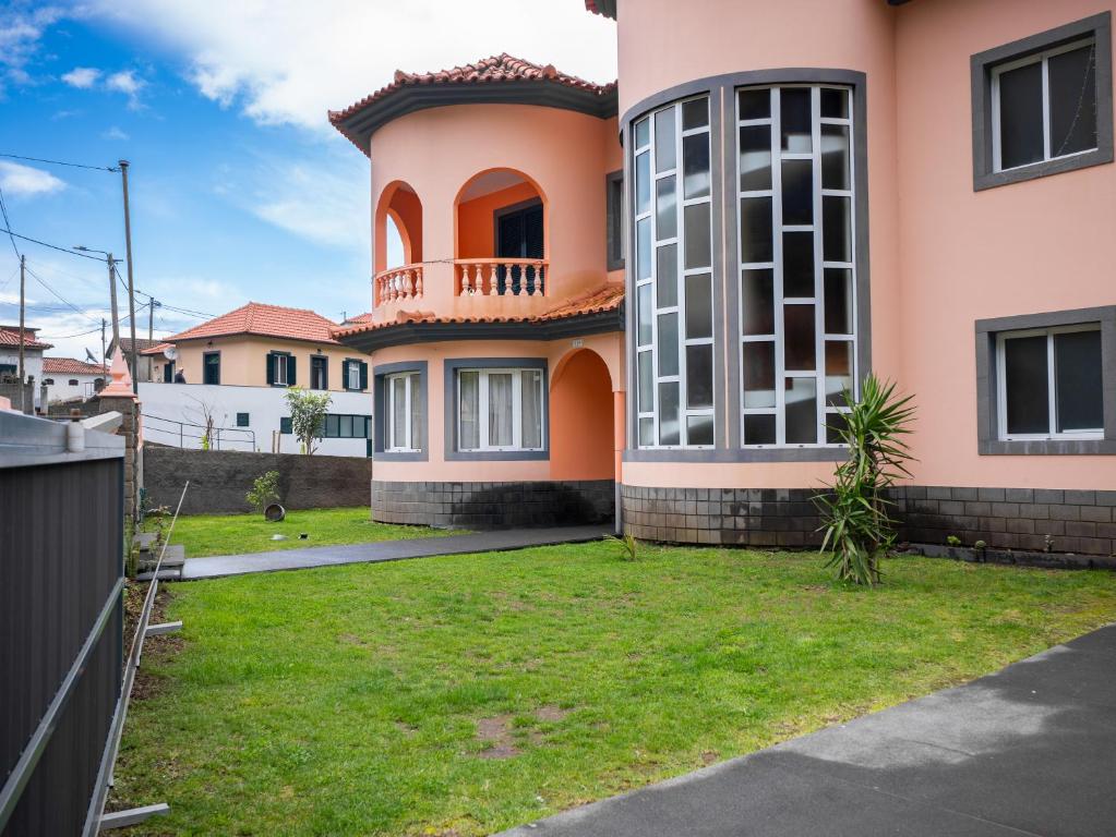 a pink house with a green yard at The Orange House, By OP in Boaventura