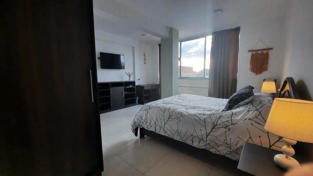a bedroom with a bed and a flat screen tv at Apartamento moderno y comodo in Cochabamba