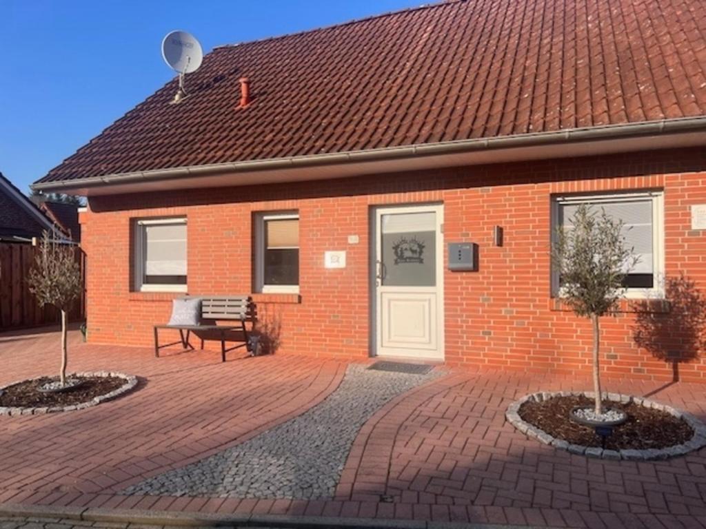 a brick house with a white door and a bench at Haus Rehkitz RE07 in Sögel